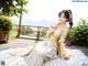 A woman in a yellow and white dress sitting on a patio.