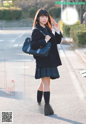 A woman in a school uniform is walking down the street.