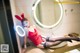 A woman in a red dress sitting on a sink in a bathroom.