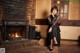 A woman sitting in front of a fireplace in a room.