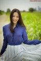 A woman in a blue shirt and white skirt posing for a picture.