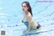 A woman in a blue and yellow bikini sitting in a pool.