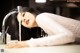 A woman laying on a counter next to a faucet.