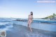 A woman in a pink bikini sitting on a boat on the beach.