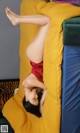 A woman laying on top of a bed in a red dress.