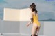 A woman in a yellow bathing suit standing on top of a roof.