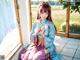 A woman in a blue and pink kimono sitting on a window sill.