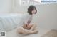 A woman sitting on the floor in front of a bed.