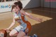 A girl in a basketball uniform crouching on a basketball court.