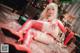 A woman in a red outfit sitting on the floor next to a Christmas tree.