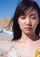 A woman with her eyes closed on the beach.