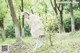 A woman in a white dress standing in the woods.